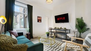 Ein Wohnzimmer mit Sofa, Couchtisch, Fernseher und einem Essbereich mit Tisch und Stühlen.