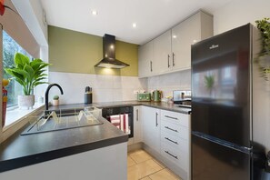 A modern kitchen with a central island, stainless steel appliances, and a large refrigerator. - Modern 4BR With Easy Access to Town and Station (Darlington)