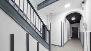 Un interior moderno con una escalera, un pasillo y una puerta.