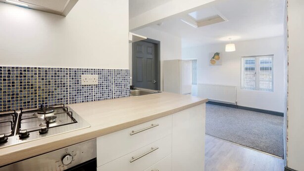 Una cocina con estufa a gas, microondas y salpicadero de azulejos.
