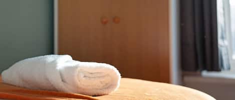 Una toalla blanca doblada cuidadosamente sobre una cama de madera.
