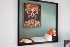 A framed artwork on a wall above a bed with a white pillow and an orange pillow. - 4BR Mitchell Street Apartment Sleeps 6 by Stay With Us (Stanley)
