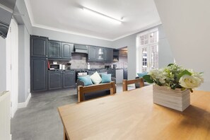 Eine moderne Küche mit grauen Schränken, einem Holzesstisch und einem Blumenstrauß.