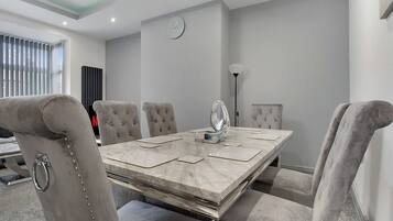 A conference room with a marble table, cushioned chairs, a clock on the wall, and a radiator in the background.