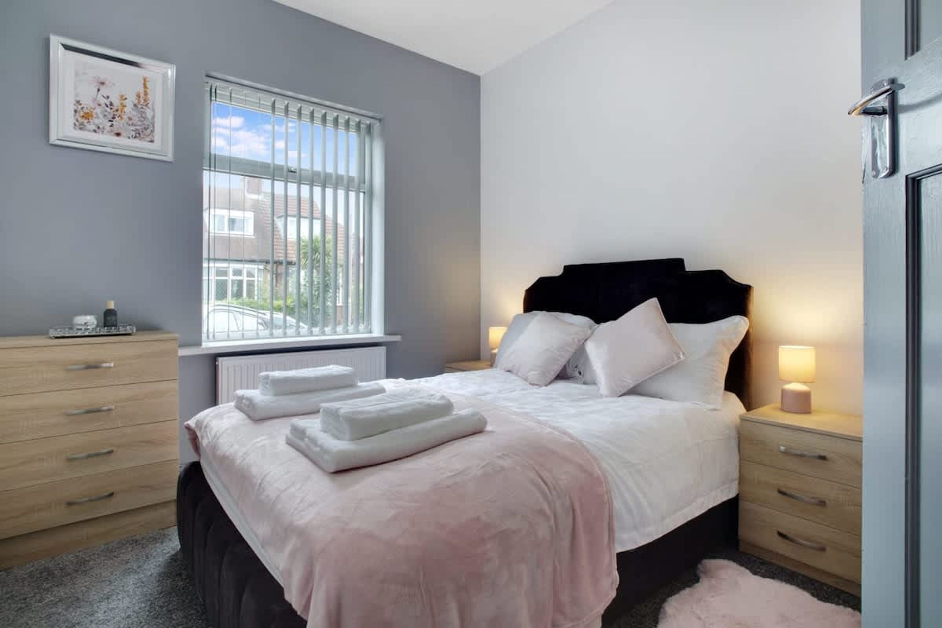 A bedroom with a bed, bedside tables, a window, and a radiator.