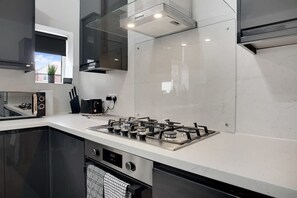 A modern kitchen with a gas stove, a range hood, and a window with a view. - 3 Bedroom With Backyard 10 Min to City Centre (Newcastle-upon-Tyne)