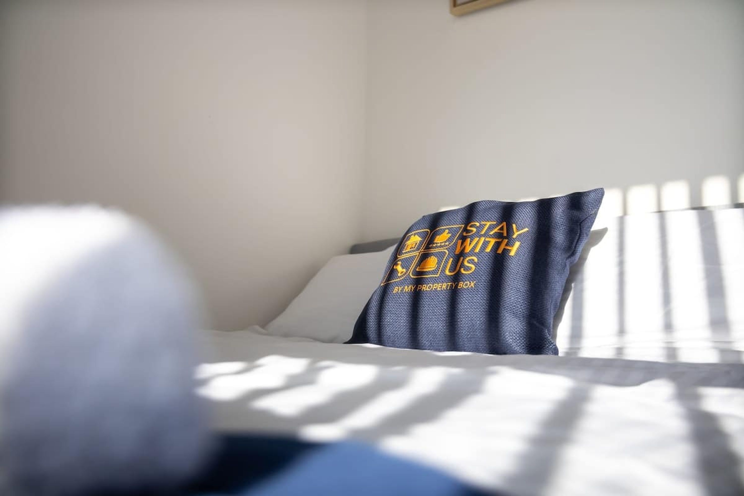 Una cama con ropa blanca y una almohada con logotipo y texto.