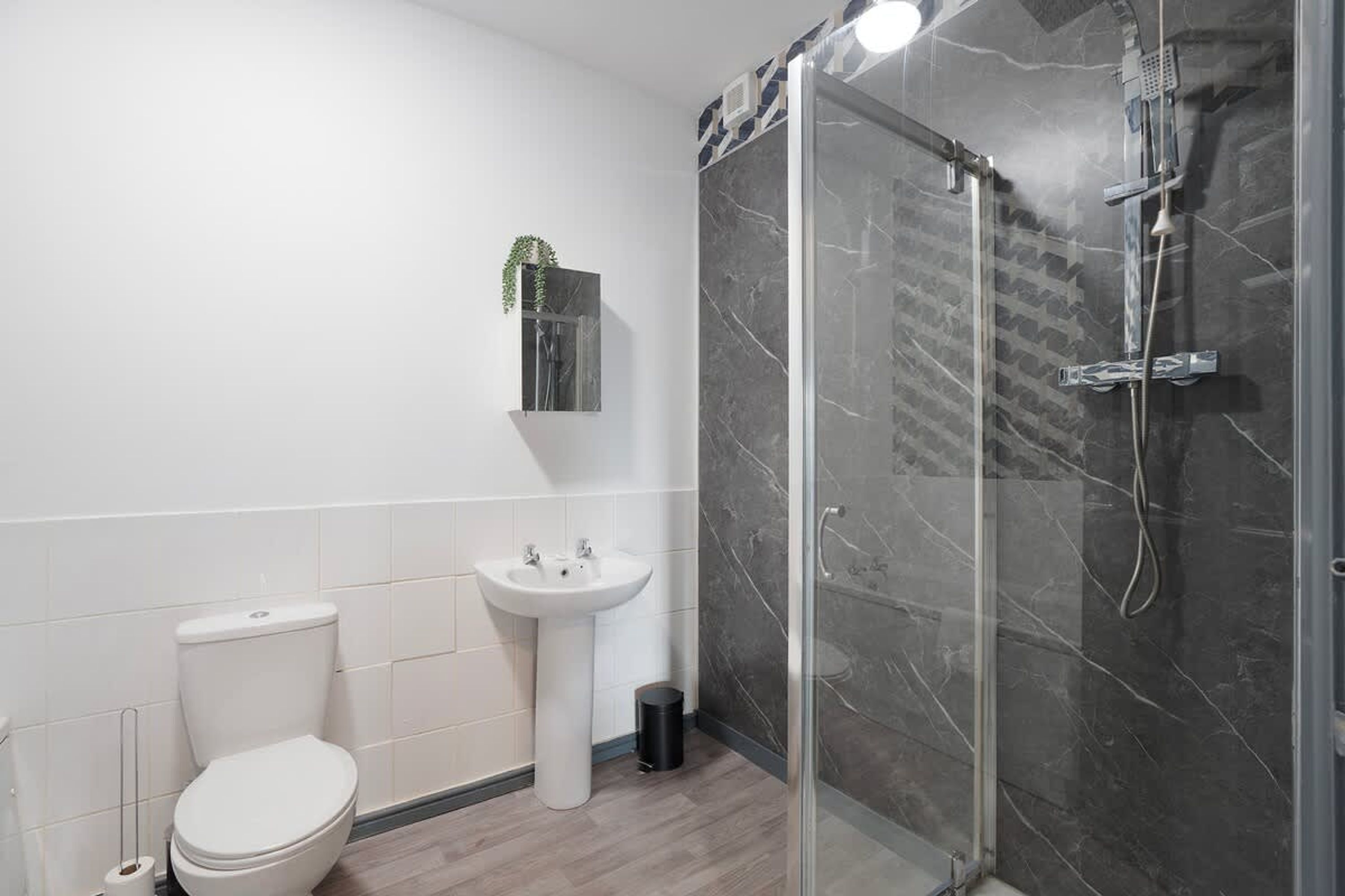 A modern bathroom with a toilet, sink, and glass-enclosed shower.