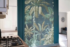 A modern kitchen with a gas stove, white cabinets, and a blue accent wall with a tropical leaf pattern. - 4 Bedroom With Private Parking and Wifi (Stockton-on-Tees)