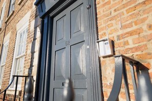 A dark-colored door with the number 82, a brick wall, and a metal gate. - 4 Bedroom With Private Parking and Wifi (Stockton-on-Tees)