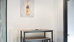Et værelse med et bord, en bænk, en radiator og et billede i ramme på væggen.