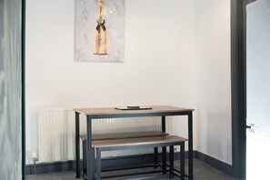 A room with a table and bench, a radiator, and a framed artwork on the wall. - 4 Bedroom With Private Parking and Wifi (Stockton-on-Tees)