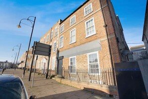 A multi-story brick building with a flat facade, large windows, and a gated entrance. - 4 Bedroom With Private Parking and Wifi (Stockton-on-Tees)