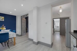 A modern kitchen with a refrigerator, a dining area with a table and chairs, and a hallway leading to another room. - Newcastle 2BR Sleeps 5 2 Parking by Stay With Us (Newcastle-upon-Tyne)