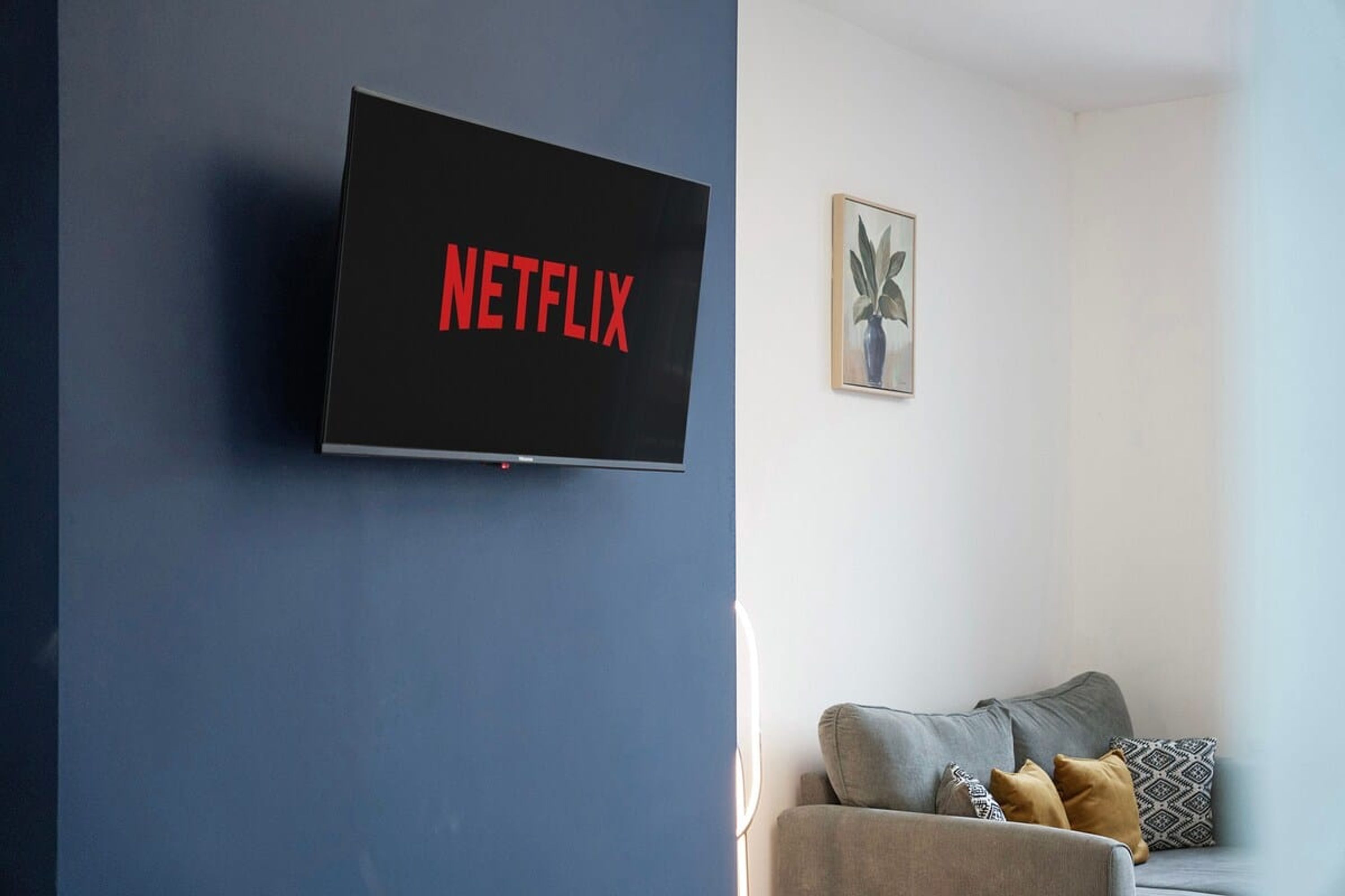 A living room with a flat-screen TV mounted on a blue wall displaying the Netflix logo.