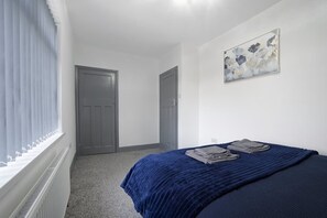 A bedroom with a bed, a door, a radiator, and a window with curtains. - Newcastle 2BR Sleeps 5 2 Parking by Stay With Us (Newcastle-upon-Tyne)