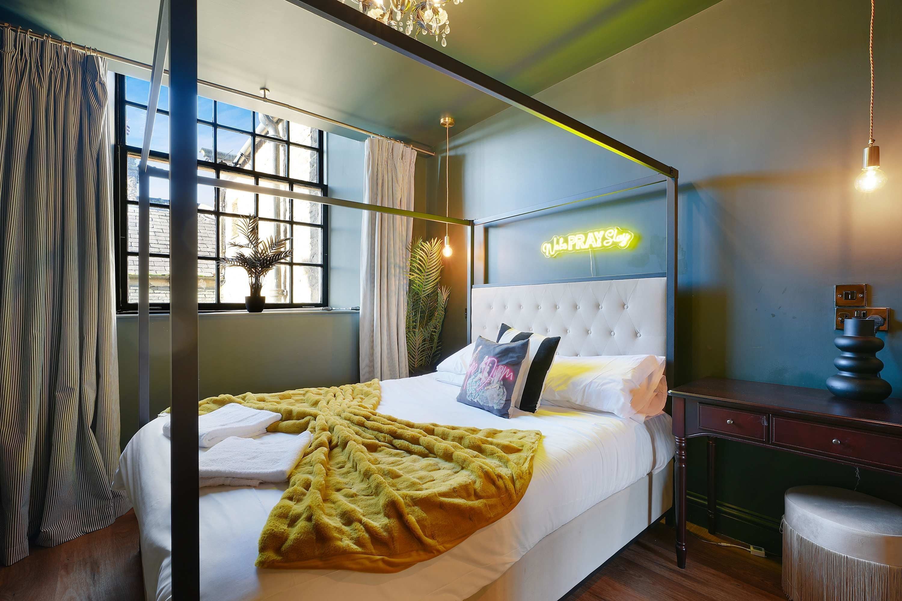 Un dormitorio moderno con una cama, un letrero de neón y una ventana con cortinas.