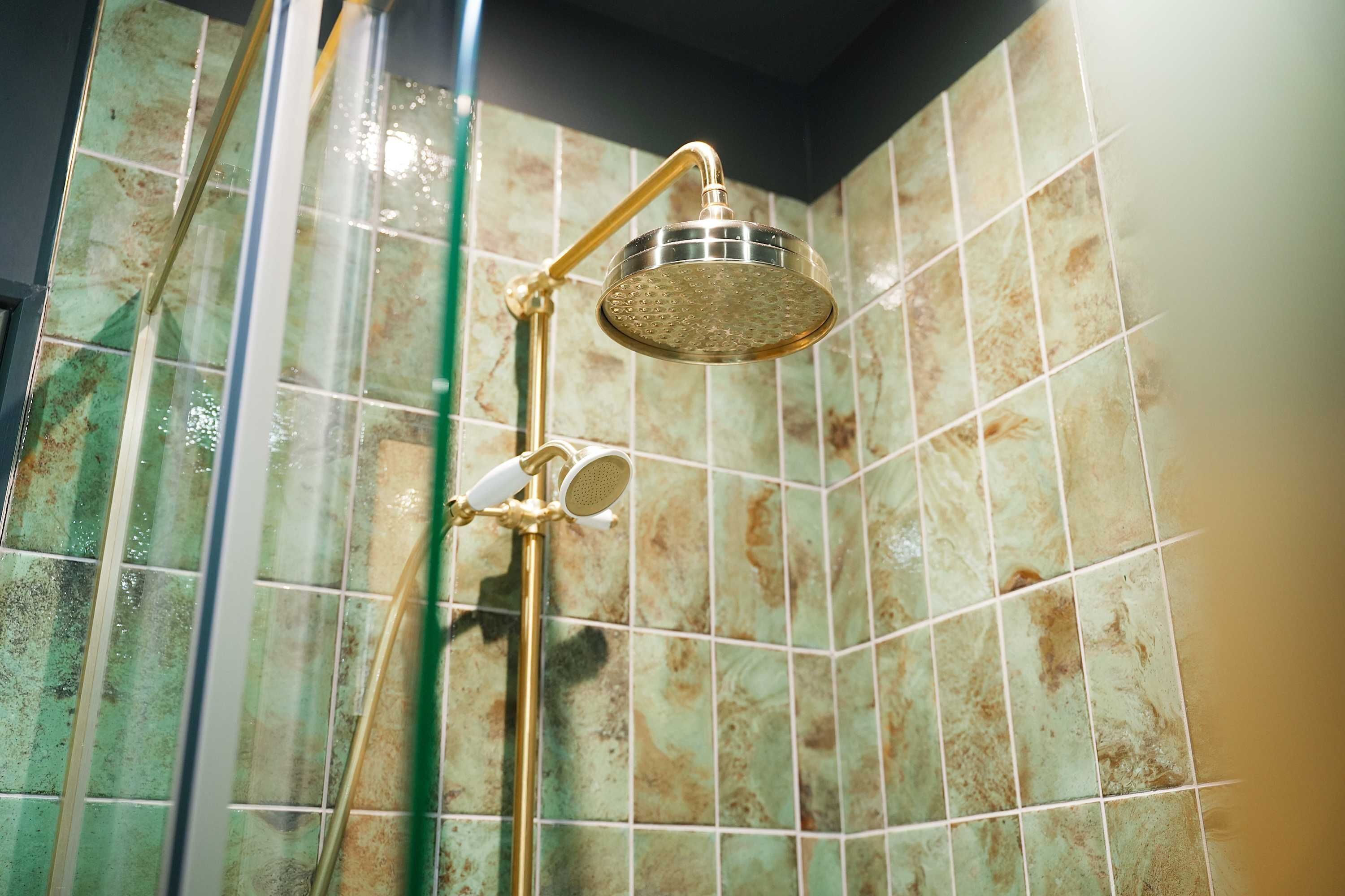 Ducha con cabezal dorado y un rociador de mano.
