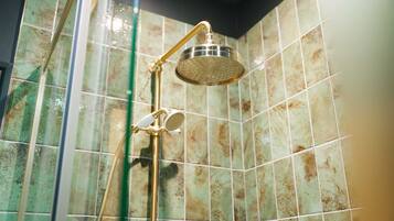 Ducha con cabezal dorado y un rociador de mano.