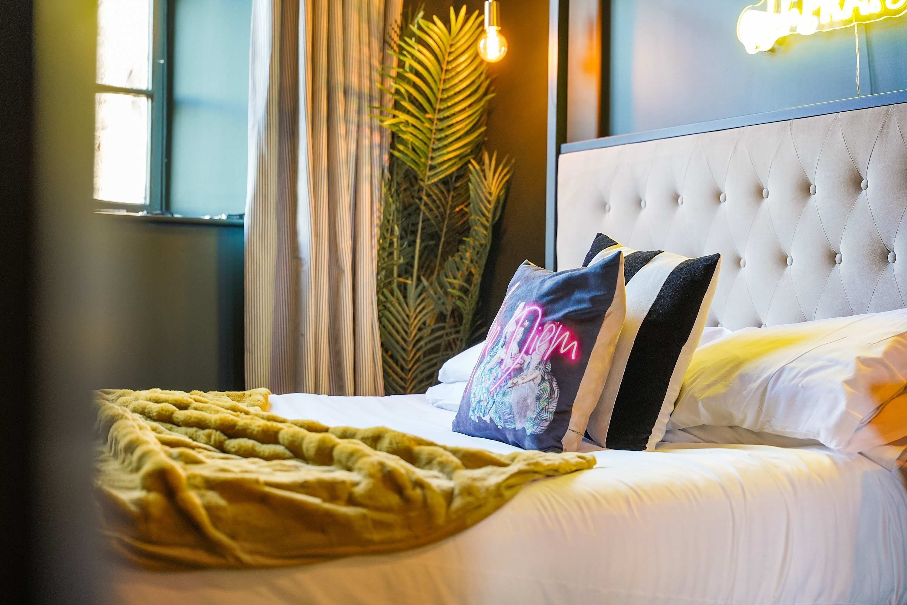 A neatly made bed with a yellow blanket, a tufted headboard, and decorative pillows.