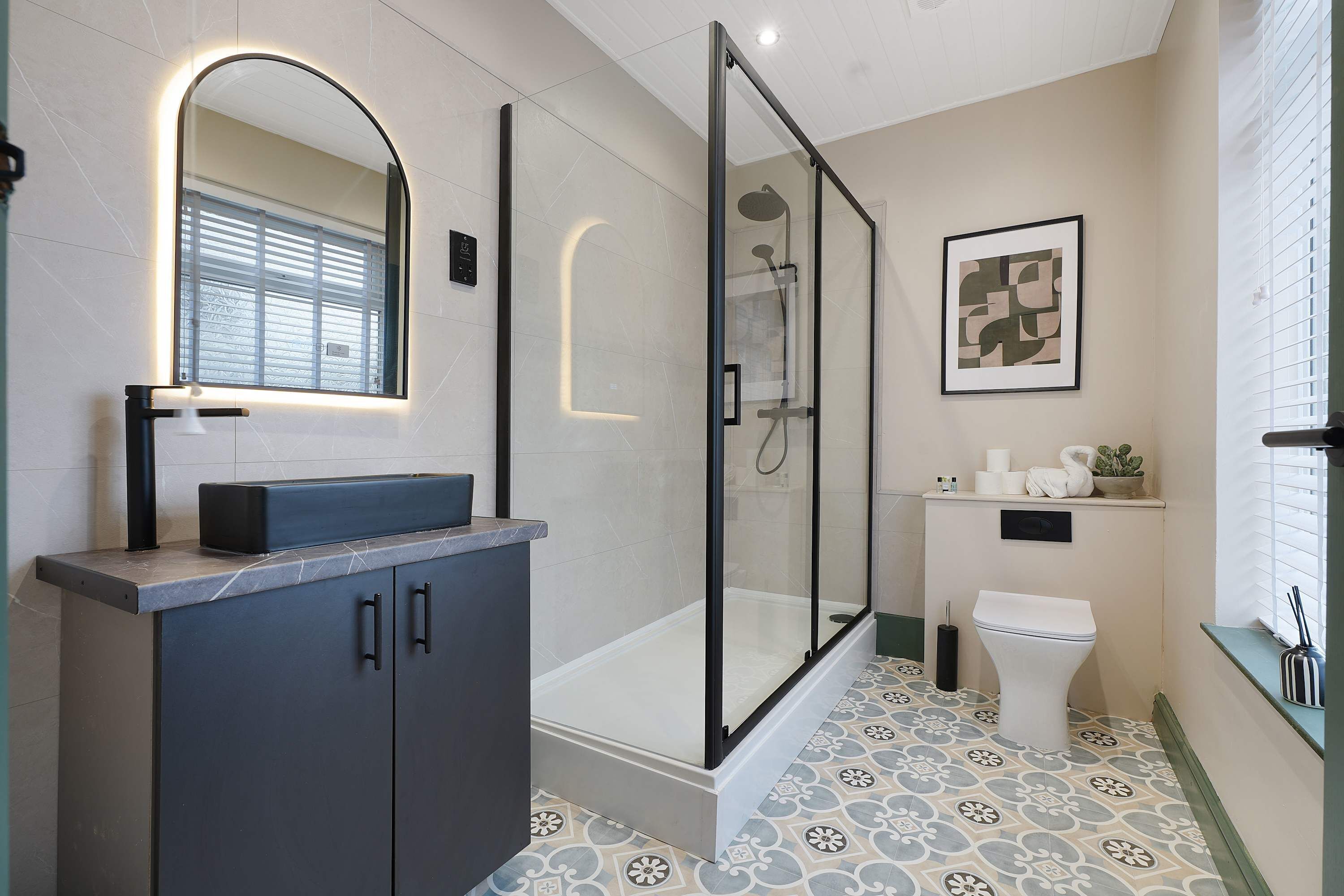 A modern bathroom with a glass-enclosed shower, a vanity with a mirror, and a toilet.