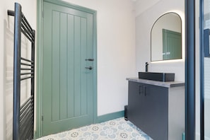 Une salle de bain avec une porte verte, un lavabo avec un miroir et des carreaux de sol à motifs.