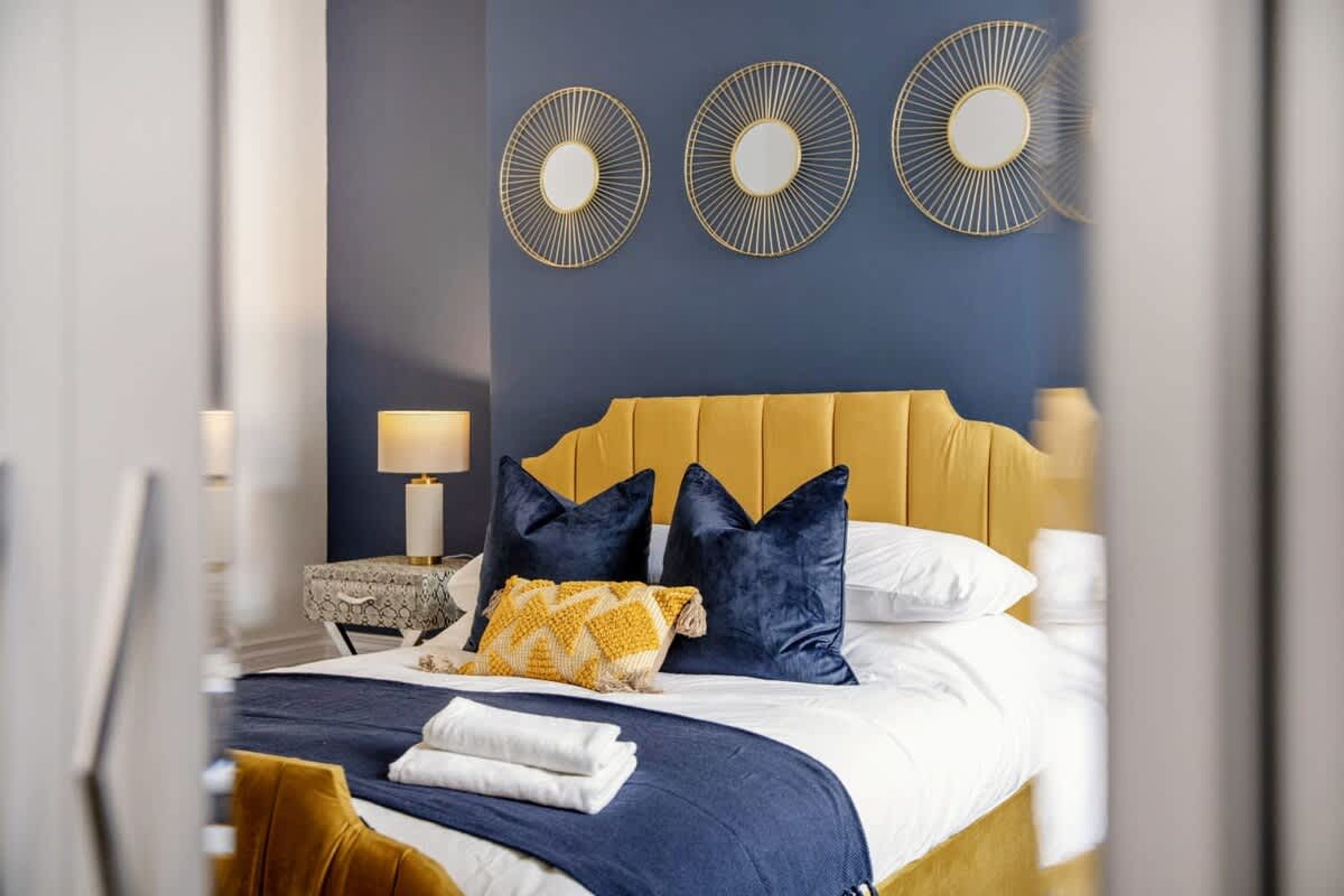 A hotel room with a bed, a nightstand, and three wall-mounted circular mirrors.