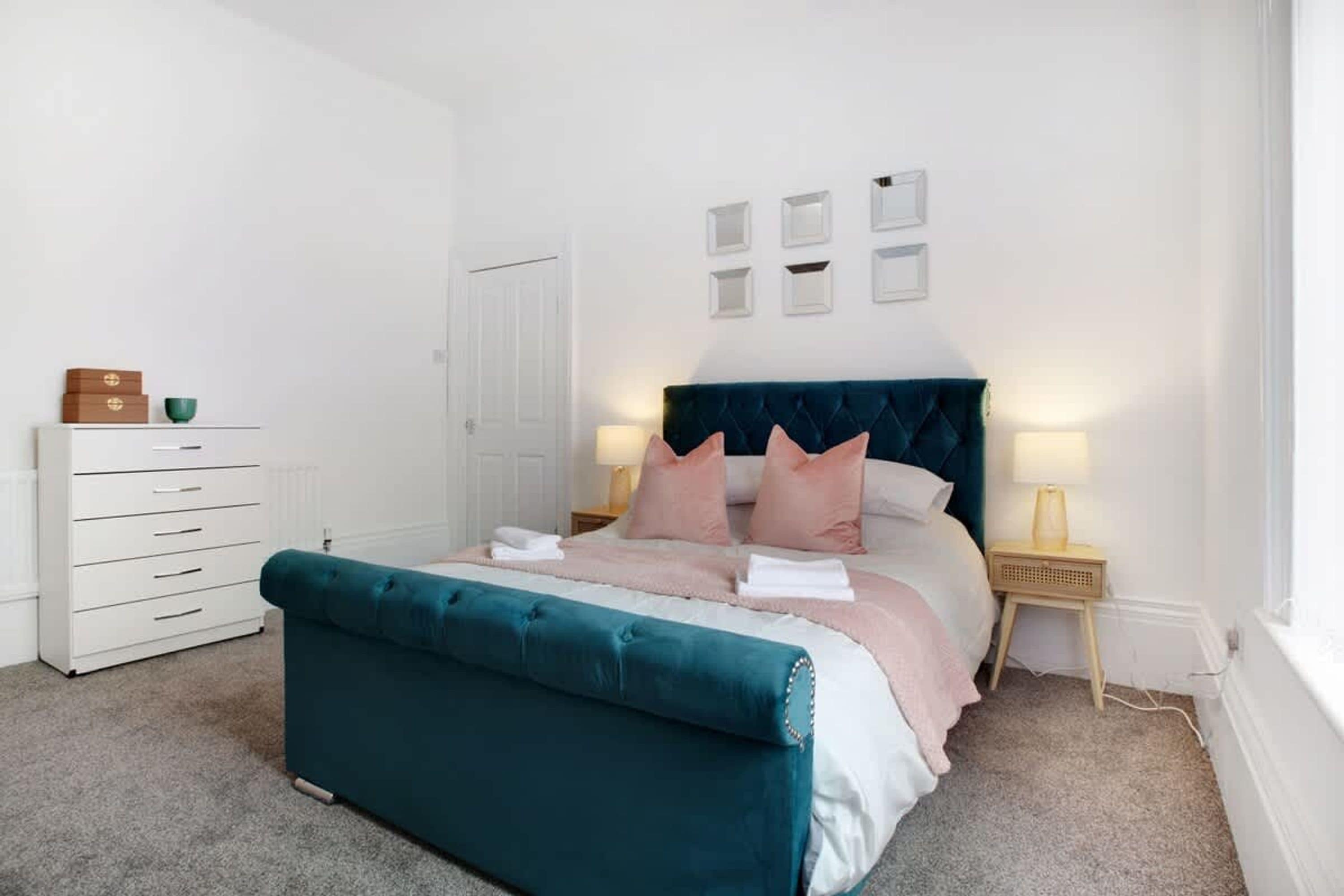 A bedroom with a bed, a dresser, a nightstand, and a door.