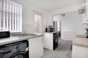 Cocina compacta con lavadora integrada, microondas y lavabo.
