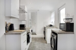 A modern kitchen with white cabinetry, a built-in oven, a microwave, and a sink. - Spacious Home for Groups Contractors Free Wifi (Sunderland)
