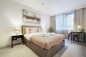 A modern hotel room with a large bed, bedside tables, a desk, and a window with curtains. - Modern 1-bed Manchester City Centre Apartment (Salford)