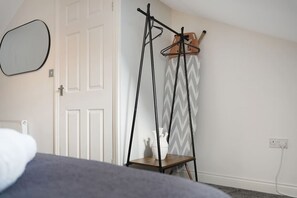 Une pièce comprenant un lit, un porte-manteau avec des cintres, un radiateur et une porte.