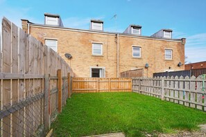 Un bâtiment en briques de deux étages, doté d’une cour arrière clôturée et surplombant un ciel dégagé.