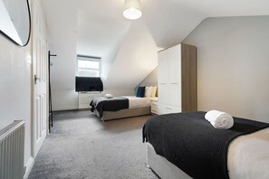 Ein modernes Schlafzimmer mit Bett, Kommode, Spiegel und Fenster.