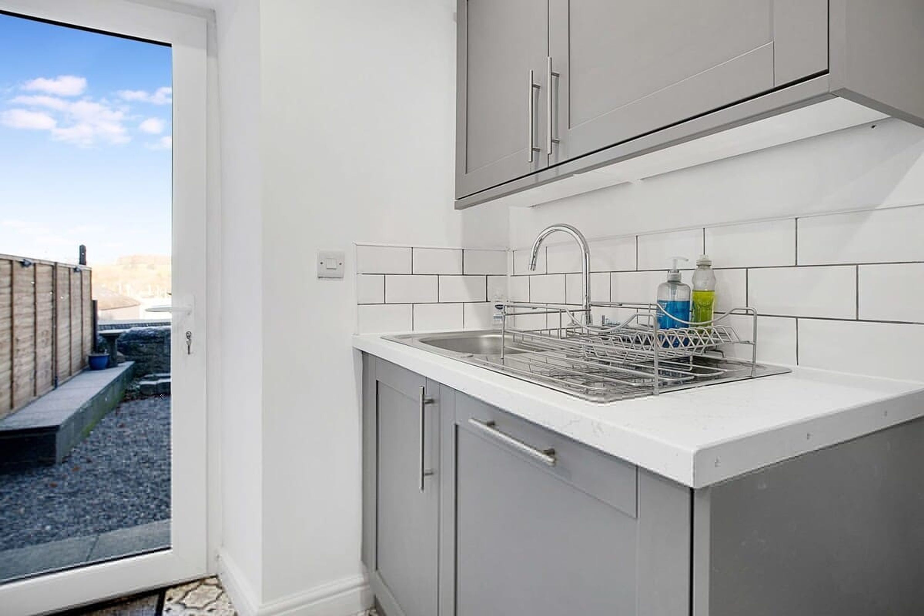 A kitchen with a sink, cabinets, and a window.