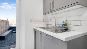 A kitchen with a sink, cabinets, and a window.