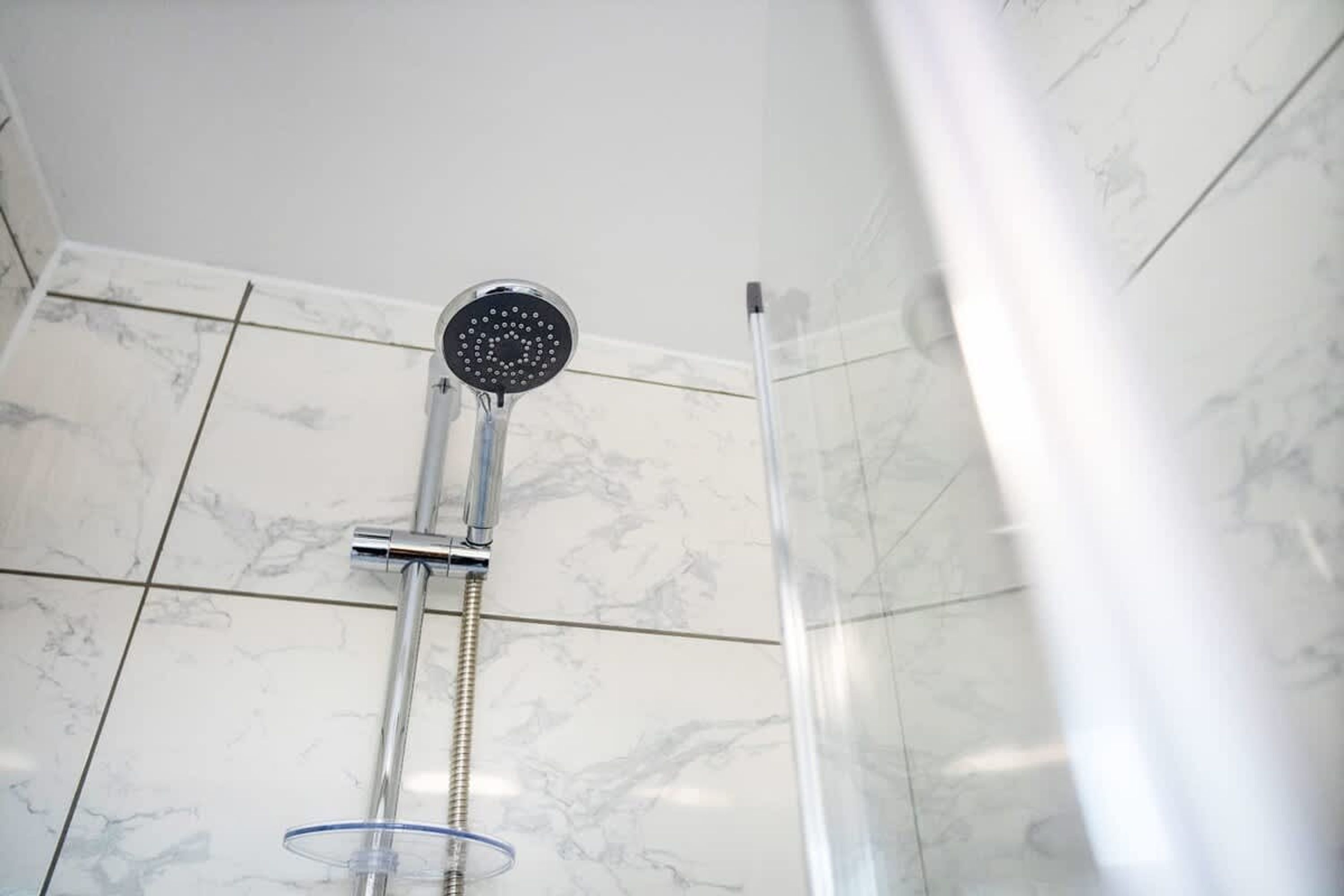Une douche équipée d’un pommeau de douche à main et d’une porte en verre.