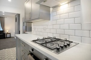 Una cocina moderna con estufa a gas, armarios grises y azulejos blancos tipo metro.