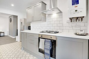 A modern kitchen with white cabinetry, a built-in oven, and a gas stove.