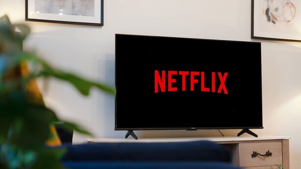 Uma televisão com o logotipo da Netflix sobre um móvel em um quarto.