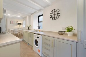 A modern kitchen with a built-in washing machine, a large window, and a wall clock. - Detached Three Bedroom Family Home Hot Tub Stay (Barnard Castle)