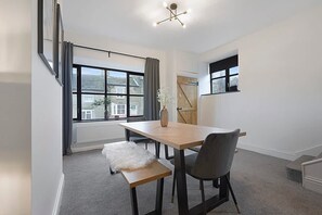 Ein modernes Zimmer mit großem Fenster, einem Esstisch und einer Bank.