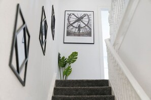 Uma escada com um relógio emoldurado e arte abstrata nas paredes.