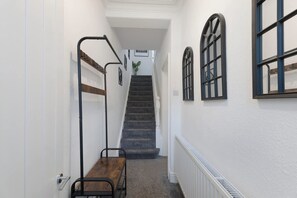 A narrow hallway with a wooden bench, a staircase, and a radiator on the wall. - Central Darlington Sleeps 8 With Wifi and Parking (Darlington)