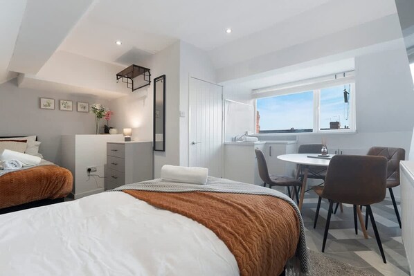 Habitación de hotel moderna con dos camas, un escritorio, una silla y ventana con vistas.