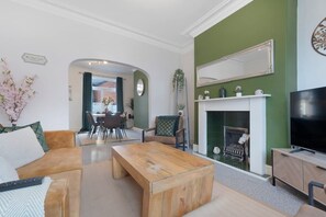 Una sala de estar con chimenea, televisor y un comedor al fondo.