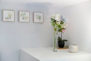 Um balcão de atendimento com um vaso de flores e três ilustrações botânicas emolduradas na parede.