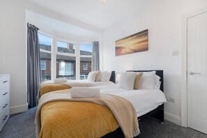 Una habitación de hotel con una cama grande, un escritorio y un ventanal con cortinas.