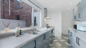 Una cocina moderna con un ventanal amplio, electrodomésticos de acero inoxidable y piso a cuadros.