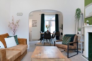 Una sala de estar con sofá, sillón, mesita de centro y un comedor con sillas y mesa.